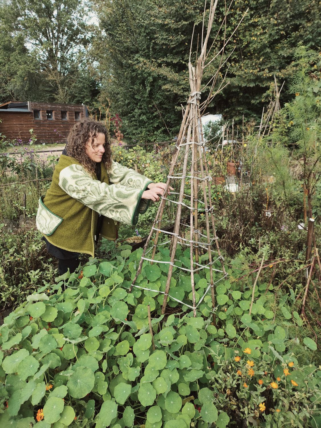 Anneke bindt een tipi van takken aan