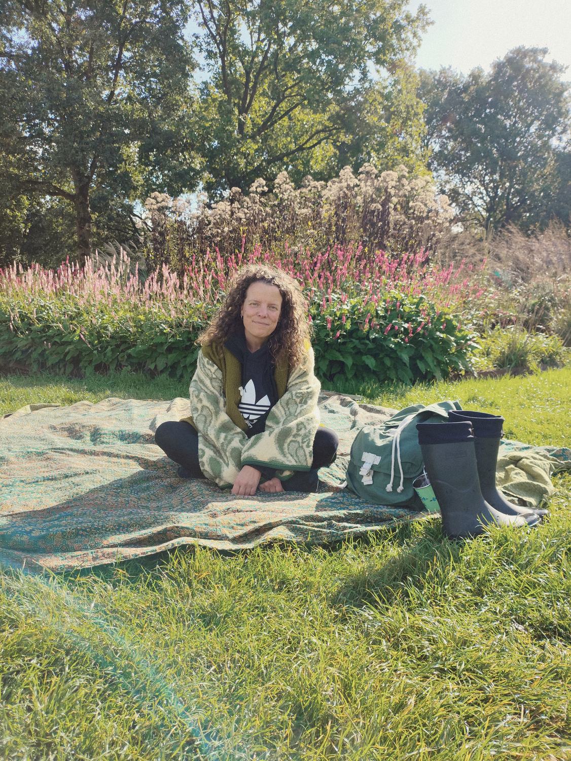 Anneke zit glimlachend op een kleed in het gras