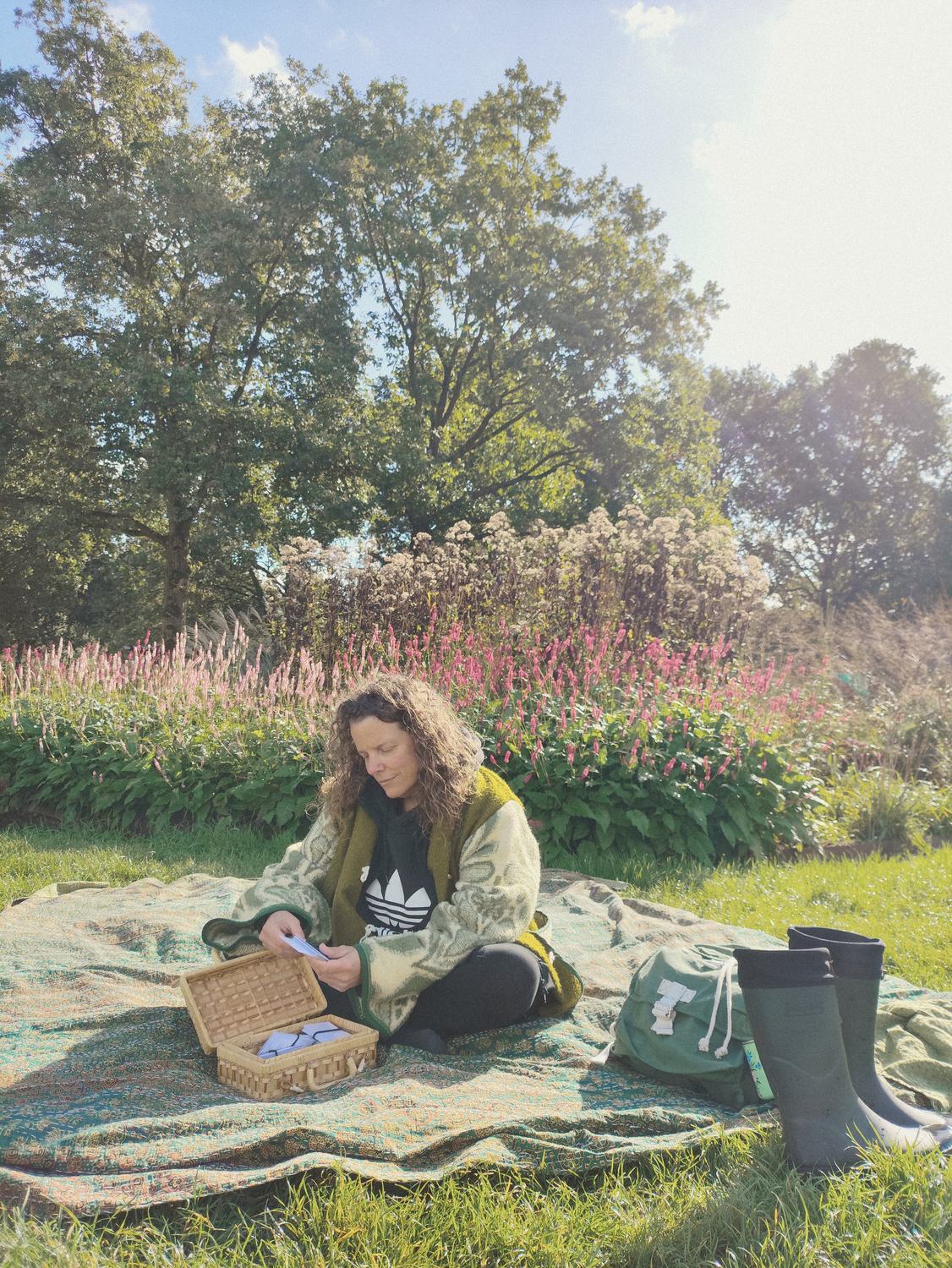 Anneke op een kleed in het gras, met haar kaartenmand