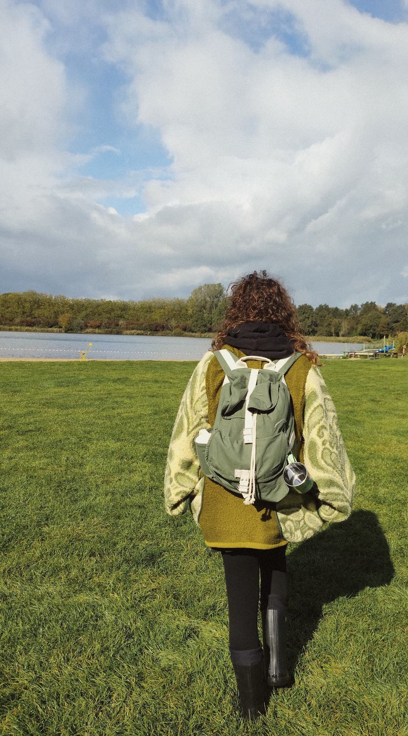 Anneke loopt met haar groene rugzak naar het strandje