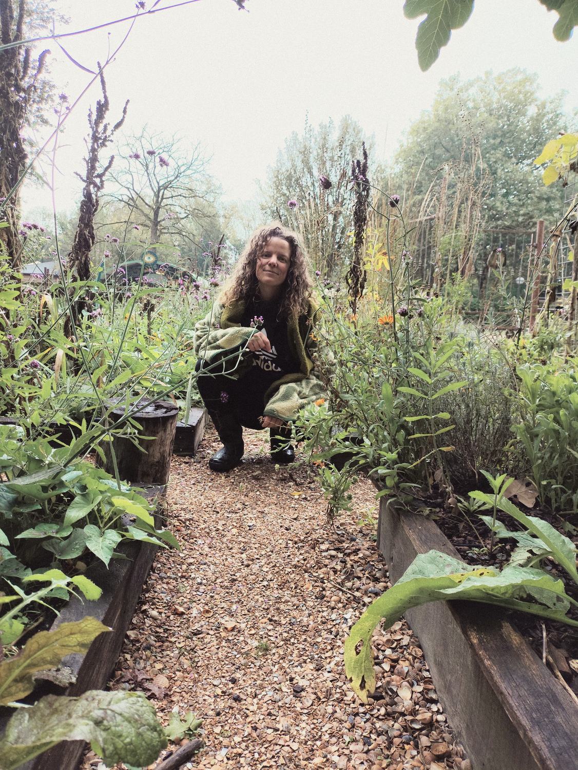 Anneke zit gehurkt op een schelpenpad in de moestuin