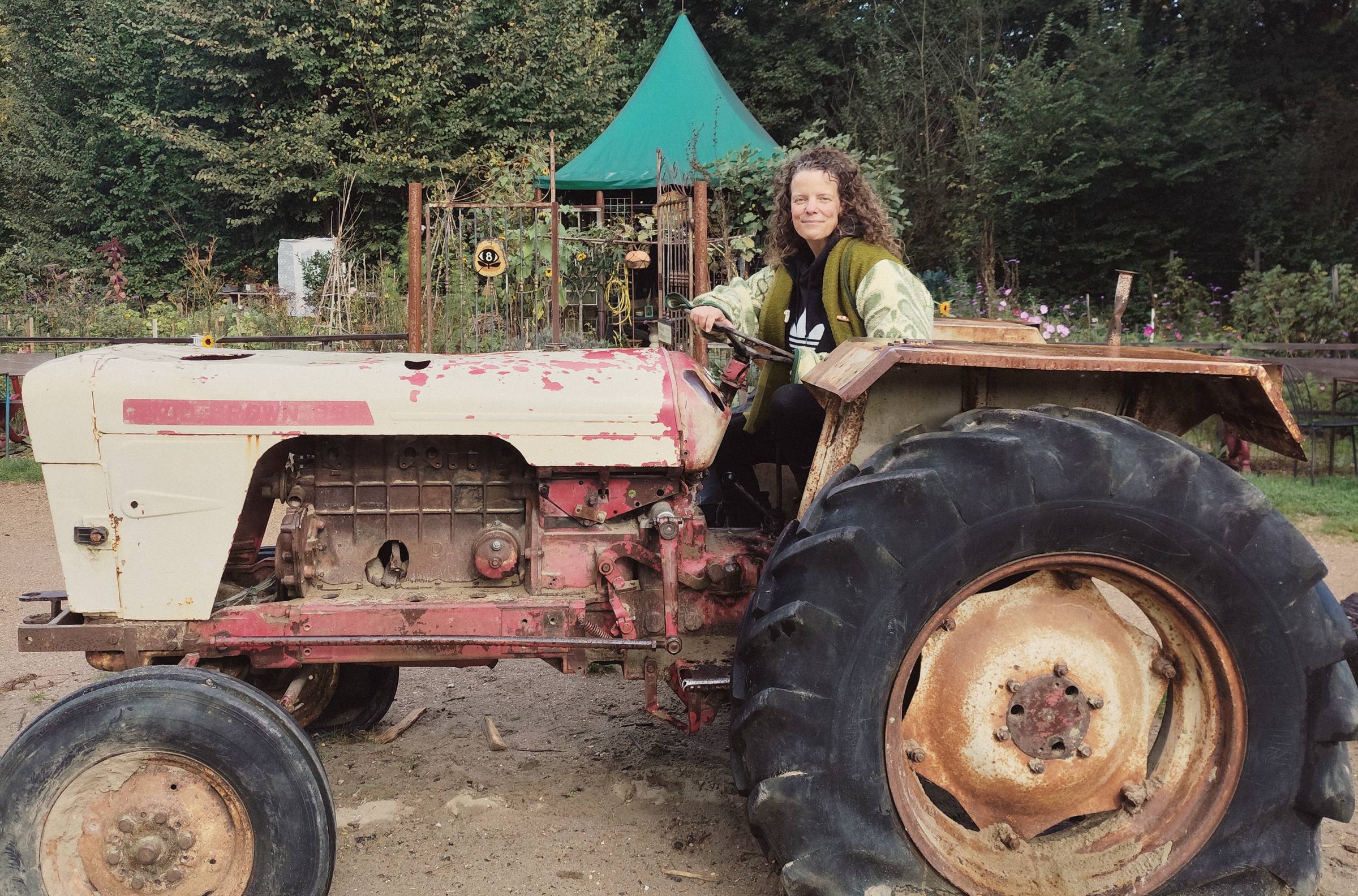 Anneke achter het stuur van een oude tractor in de tuin